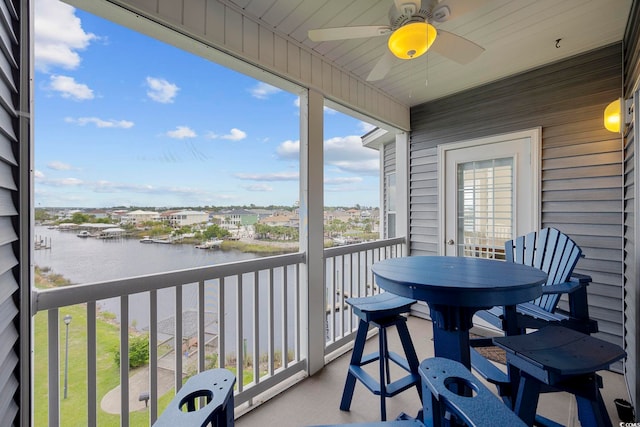 balcony with ceiling fan and a water view