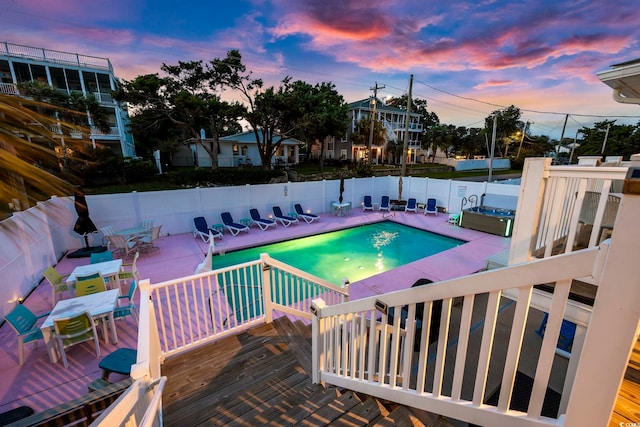 pool at dusk with a deck and a patio