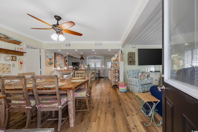 dining space featuring crown molding, light wood-type flooring, and ceiling fan