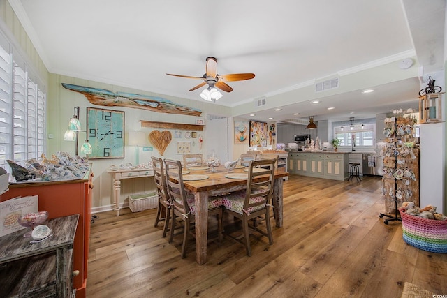 dining space with sink, crown molding, light wood-type flooring, and ceiling fan