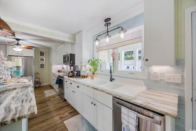 kitchen with hardwood / wood-style flooring, stainless steel appliances, backsplash, pendant lighting, and white cabinets