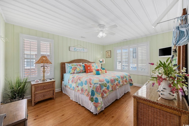 bedroom featuring ceiling fan, ornamental molding, multiple windows, and light hardwood / wood-style floors