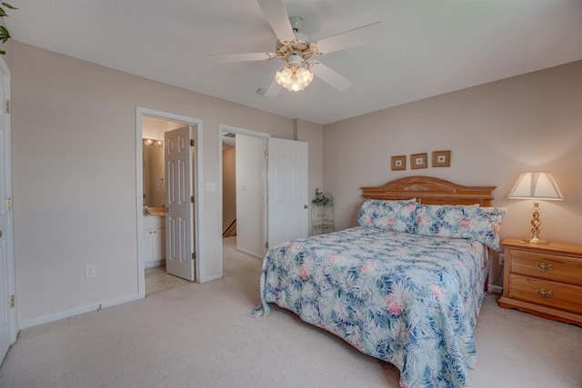 bedroom with light carpet, ceiling fan, baseboards, and connected bathroom