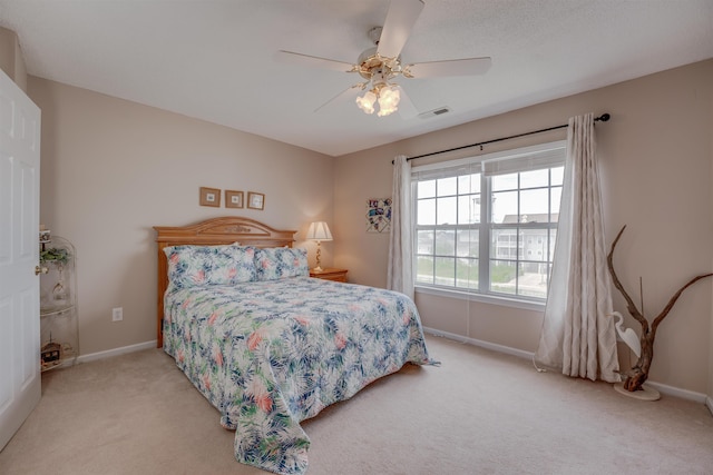 bedroom featuring baseboards, visible vents, a ceiling fan, and light colored carpet