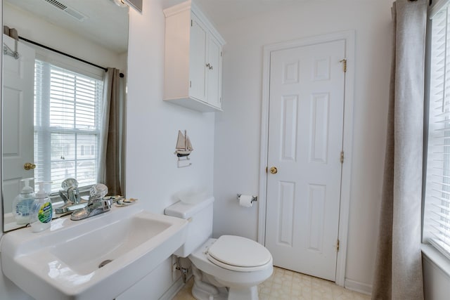 bathroom with toilet, a sink, visible vents, and tile patterned floors