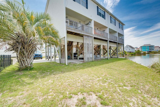 rear view of property with a water view and a lawn