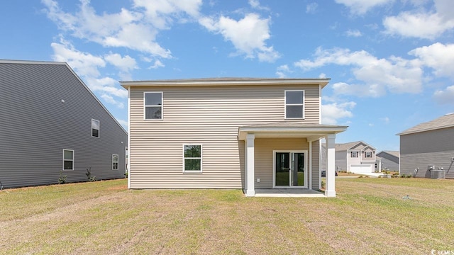 rear view of house with central AC, a patio area, and a lawn