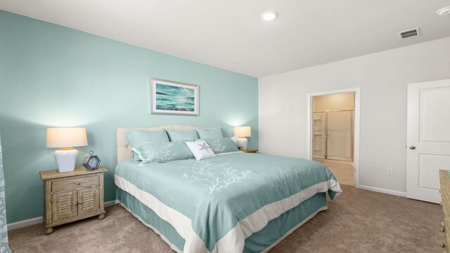 bedroom with light colored carpet and ensuite bathroom