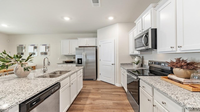 kitchen featuring appliances with stainless steel finishes, white cabinetry, sink, and light hardwood / wood-style flooring