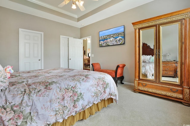 carpeted bedroom featuring ceiling fan, crown molding, and a raised ceiling