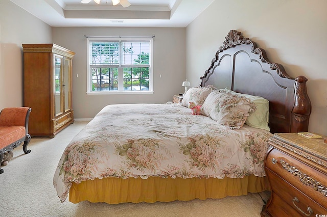 carpeted bedroom with ceiling fan and a raised ceiling