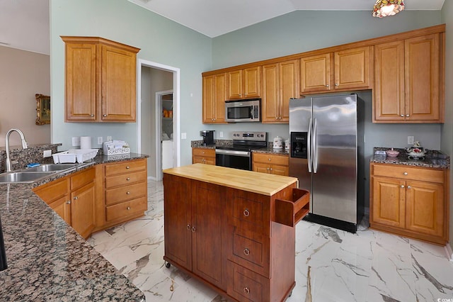 kitchen featuring sink, vaulted ceiling, appliances with stainless steel finishes, and dark stone counters