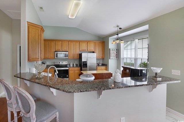 kitchen with lofted ceiling, stainless steel appliances, kitchen peninsula, and a breakfast bar area