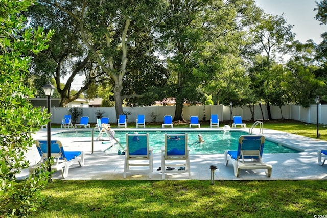 community pool with a patio area, fence, and a lawn