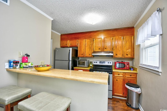 kitchen with appliances with stainless steel finishes, crown molding, a textured ceiling, kitchen peninsula, and dark wood-type flooring