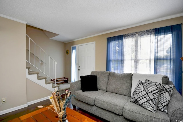 living room featuring a textured ceiling, wood finished floors, baseboards, stairway, and crown molding