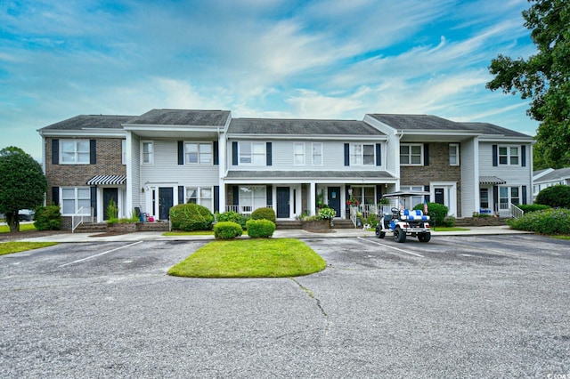 view of property featuring uncovered parking and brick siding