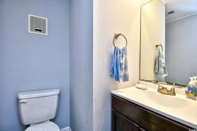 bathroom featuring ornamental molding, a textured ceiling, vanity, and toilet