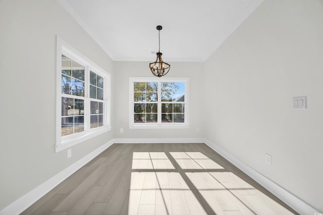 unfurnished dining area featuring a chandelier, hardwood / wood-style floors, and crown molding