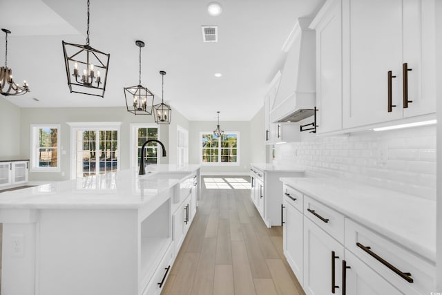 kitchen with tasteful backsplash, a healthy amount of sunlight, a spacious island, decorative light fixtures, and white cabinets