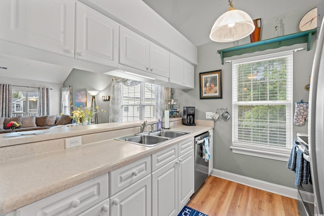 kitchen with appliances with stainless steel finishes, white cabinetry, light countertops, and a sink