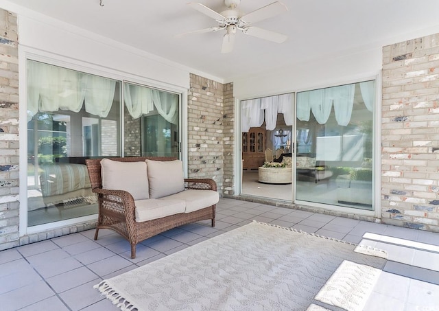 living area with light tile patterned flooring, brick wall, and ceiling fan