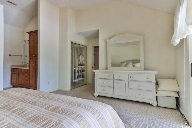 carpeted bedroom with ensuite bath, lofted ceiling, sink, and a closet