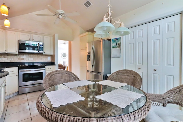 kitchen with vaulted ceiling, decorative light fixtures, light tile patterned floors, appliances with stainless steel finishes, and decorative backsplash