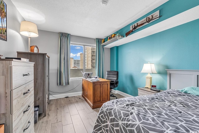 bedroom with light wood-type flooring and a textured ceiling