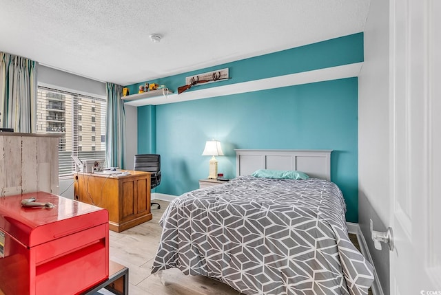 bedroom featuring a textured ceiling and light hardwood / wood-style flooring