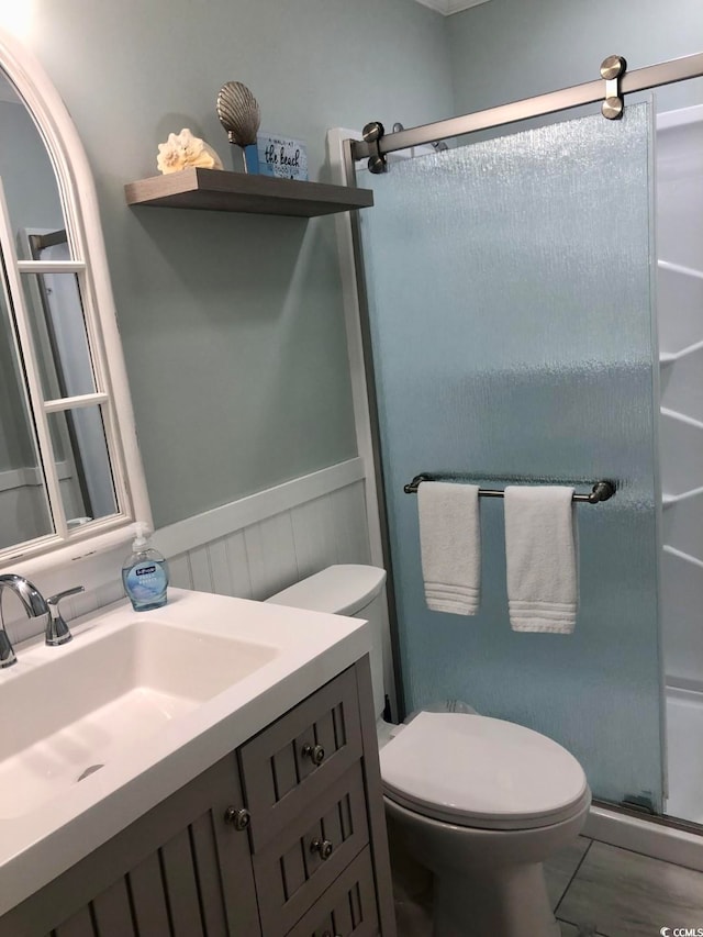 bathroom with vanity, toilet, and a shower with door