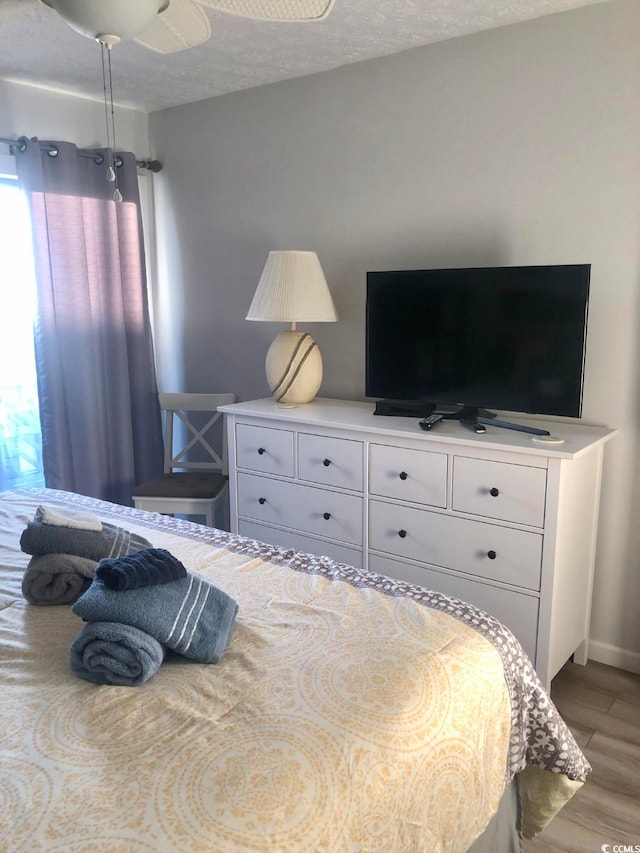 bedroom featuring ceiling fan, a textured ceiling, and light hardwood / wood-style floors