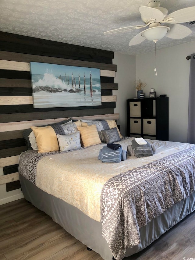 bedroom with a textured ceiling, hardwood / wood-style floors, and ceiling fan