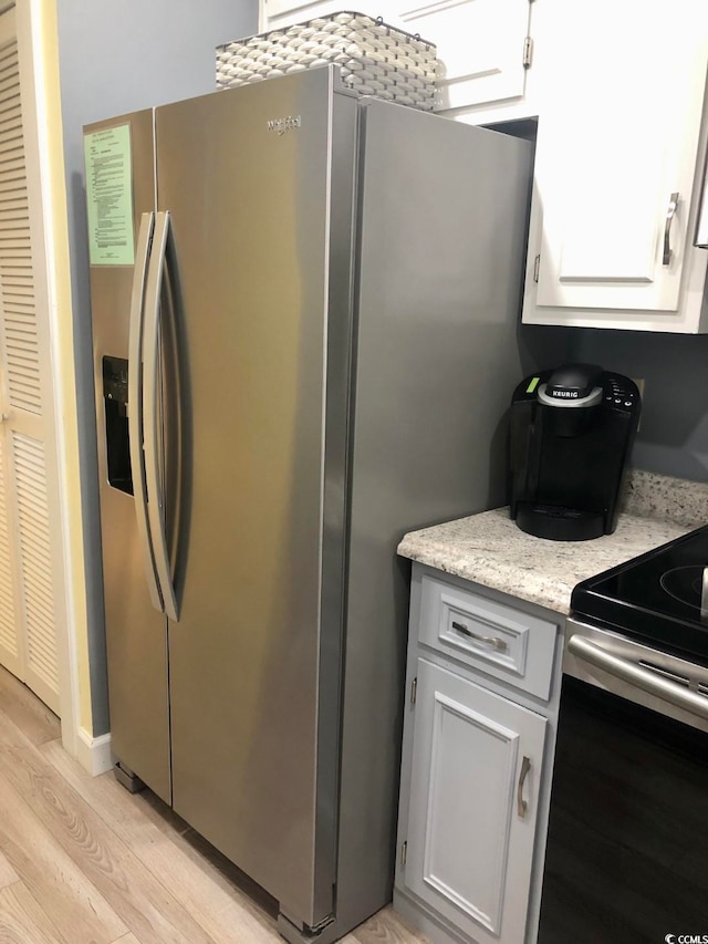 kitchen with white cabinets, light wood-type flooring, and stainless steel appliances