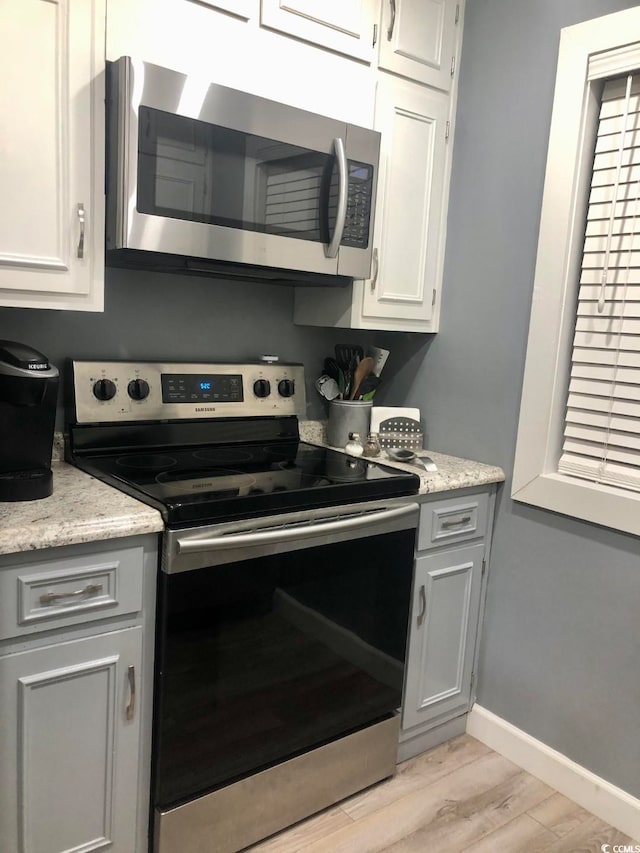 kitchen with white cabinets, stainless steel appliances, and light hardwood / wood-style flooring