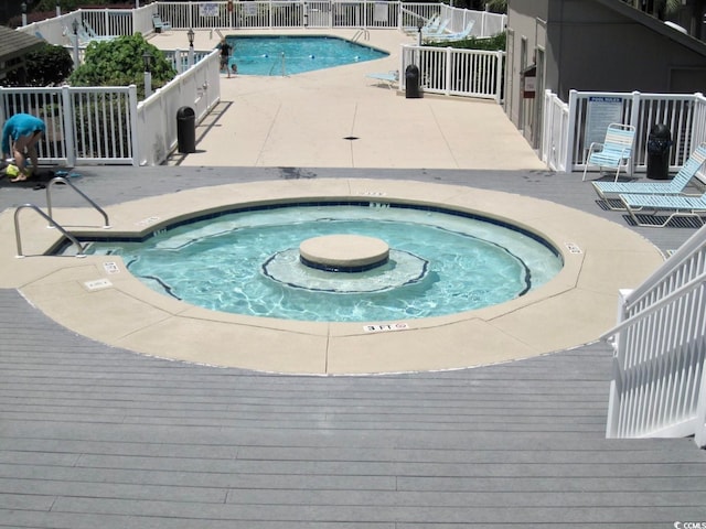 view of swimming pool featuring a wooden deck, a patio area, and a hot tub