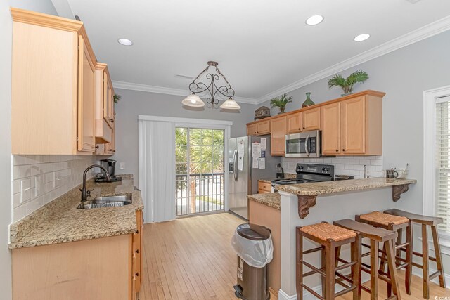 kitchen featuring a sink, ornamental molding, appliances with stainless steel finishes, a breakfast bar, and light brown cabinetry