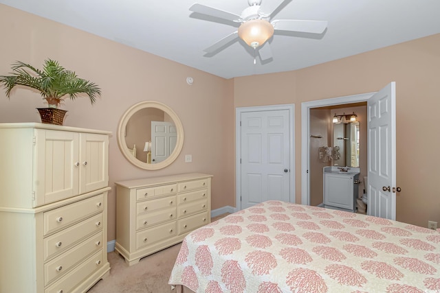 bedroom with ceiling fan, light colored carpet, and ensuite bathroom