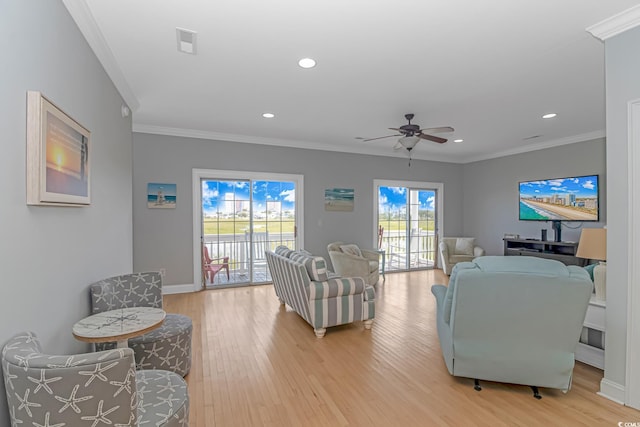 living room with crown molding, ceiling fan, and light wood-type flooring