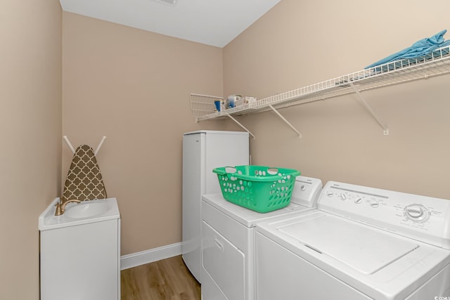 laundry area with light wood-type flooring, sink, and washing machine and dryer