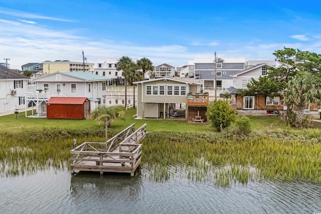 view of dock featuring a deck with water view and a lawn