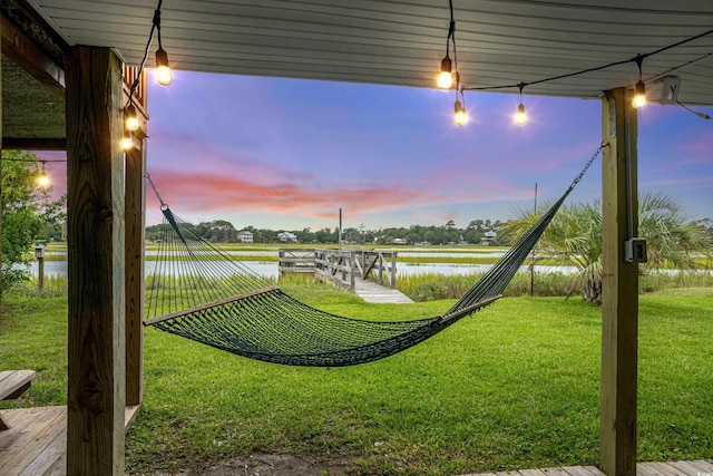 yard at dusk with a water view and a boat dock