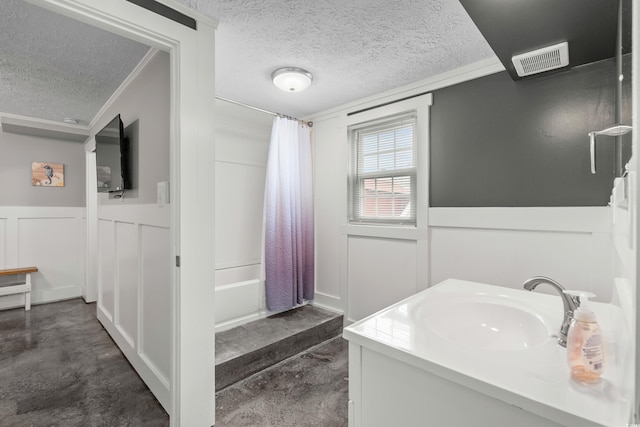 bathroom with shower / tub combo with curtain, vanity, crown molding, and a textured ceiling