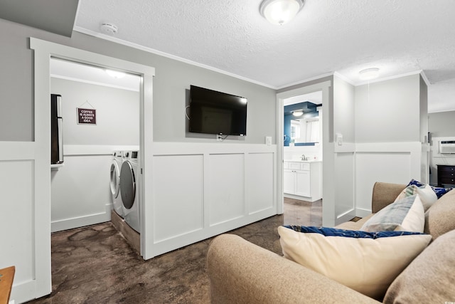 living room with washing machine and clothes dryer, ornamental molding, sink, and a textured ceiling