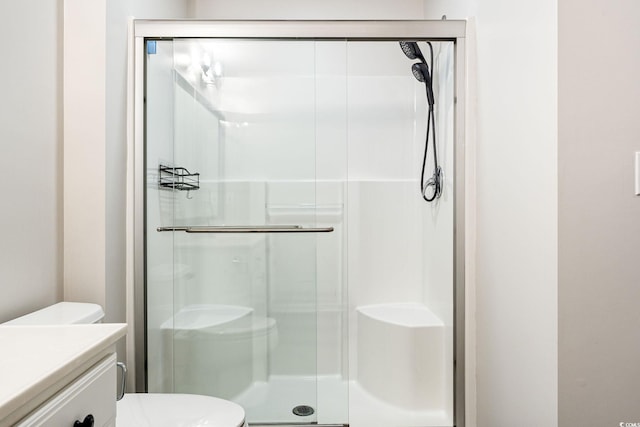 bathroom featuring toilet, a stall shower, and vanity