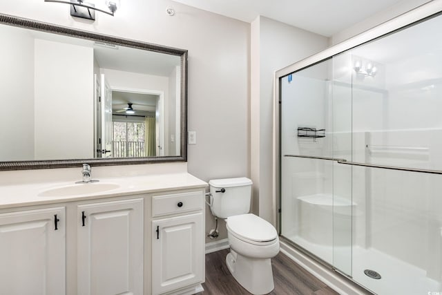 bathroom featuring toilet, a stall shower, wood finished floors, and vanity