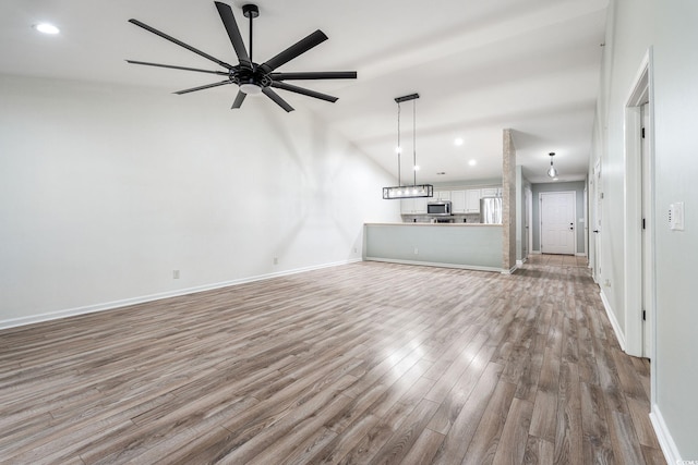 unfurnished living room featuring recessed lighting, lofted ceiling, ceiling fan, wood finished floors, and baseboards