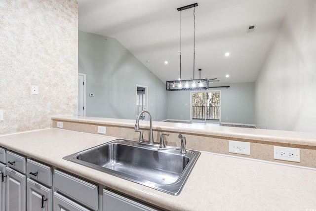 kitchen with lofted ceiling, light countertops, a sink, and decorative light fixtures