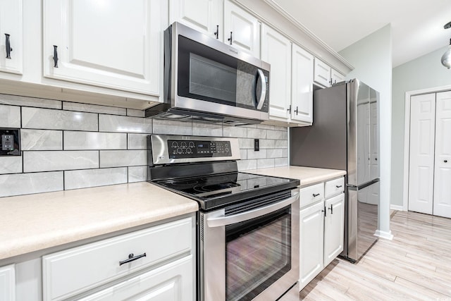 kitchen with stainless steel appliances, light countertops, and white cabinetry