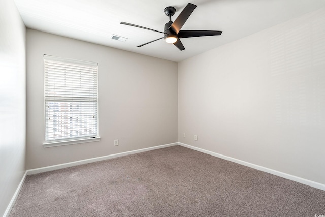 carpeted spare room featuring ceiling fan, visible vents, and baseboards